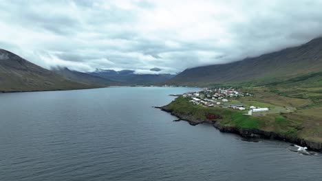 Aguas-Tranquilas-Del-Fiordo-Nordfjordur-Con-La-Ciudad-De-Neskaupstadur-Junto-A-La-Montaña-En-El-Este-De-Islandia