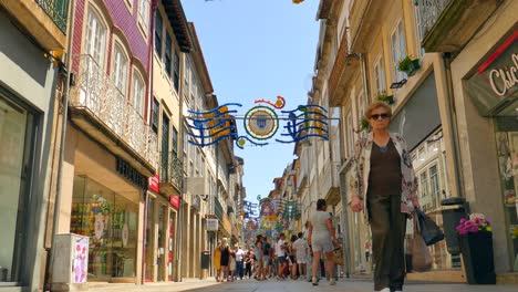 Turistas-Caminando-Por-Una-Calle-Decorada-En-Un-Día-Soleado-En-Braga,-Portugal