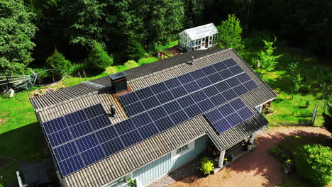 Drone-shot-circling-a-off-grid-home,-powered-by-sunlight-collectors,-summer-day