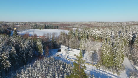 Aerial-view-orbiting-a-snowy,-solar-powered,-countryside-house,-sunny-winter-day
