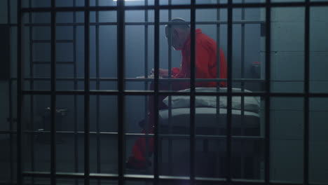 Criminal-Sits-on-the-Bed-in-Prison-Cell-Looks-at-Barred-Window----------(Stock-Footage)