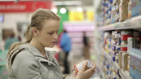 Young-woman-is-choosing-food-for-her-child-in-the-supermarket