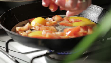 Egg-frying-in-a-pan-Adding-tomato-slices