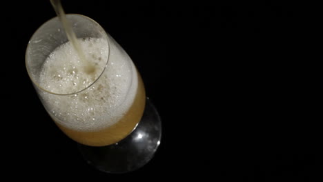 Beer-pours-in-glass-on-black-High-angle-shot