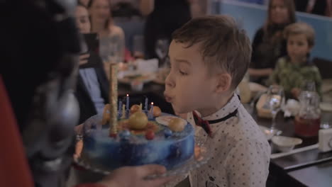 Geburtstagskind-Bläst-Kerzen-Auf-Kuchen