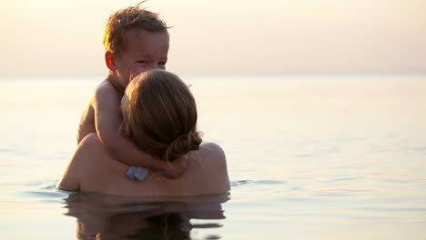 Loving-mother-hugging-with-her-son-in-the-sea