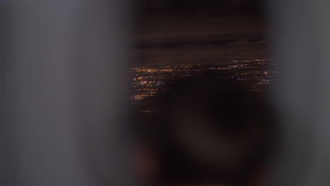 Boy-looking-at-night-city-from-plane-moving-upwards
