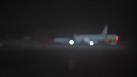 Night-view-of-plane-and-aircraft-tow-tractor-at-the-airport-defocus