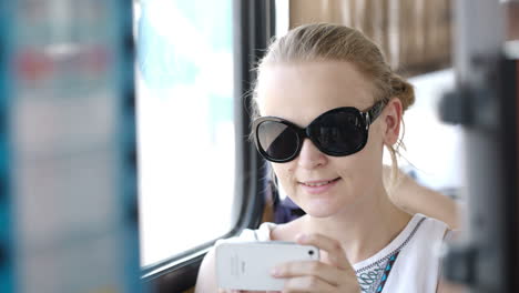Woman-taking-pictures-at-her-mobile-on-a-bus