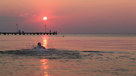Mann-Schwimmt-Bei-Sonnenuntergang-Im-Meer