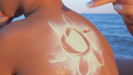 Making-sun-with-sunscreen-cream-on-childs-back