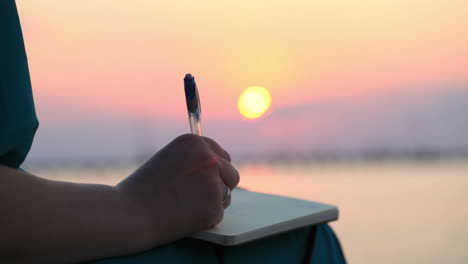 Woman-writing-in-her-diary-at-sunset