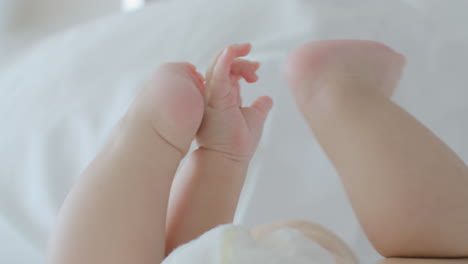 Baby-lying-on-bed-and-touching-feet