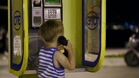 Young-boy-talking-to-the-phone-in-a-booth
