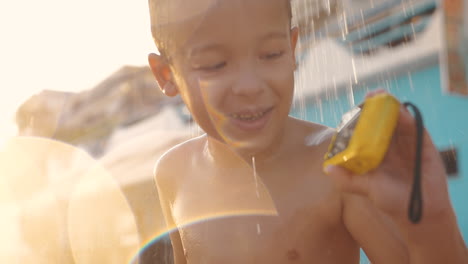 Child-taking-beach-shower-and-watching-photos-on-waterproof-camera