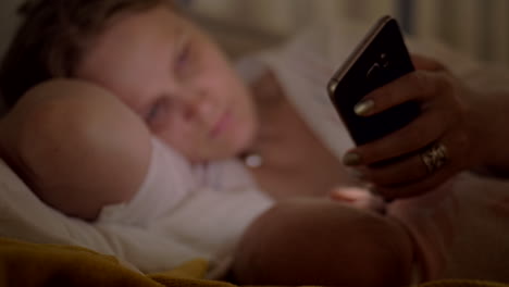 Woman-using-mobile-when-breastfeeding-baby-at-night