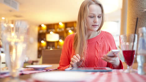 Woman-in-cafe-with-touchpad-and-phone