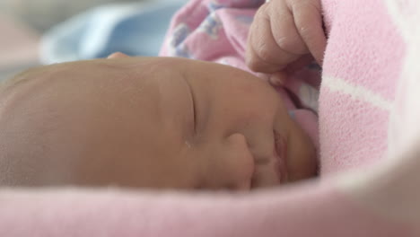 Newborn-baby-girl-asleep-wrapped-in-a-blanket