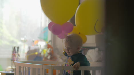 Kleines-Mädchen-Spielt-Mit-Luftballons-Im-Kinderbett