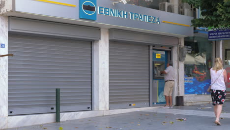 Hombre-Utilizando-Cajero-Automático-Exterior-En-La-Calle-Grecia