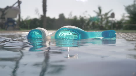 Eine-Nahaufnahme-Einer-Blauen-Schutzbrille-Auf-Einer-Offenen-Pooloberfläche-An-Einem-Sonnigen-Tag