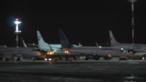A-blurred-panoramic-shot-of-airplanes-on-an-airport-courtyard-at-night