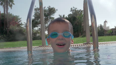 Cheerful-child-in-goggles-bathing-in-outdoor-swimming-pool