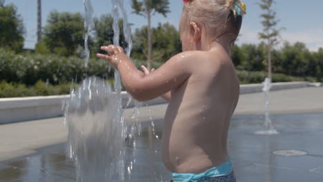 Baby-girl-having-enjoyable-summer-day-and-playing-with-fountain-jet
