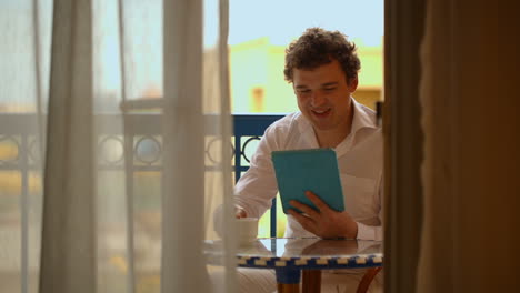 Man-with-laptop-having-tea-on-the-balcony