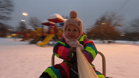 Little-child-having-exciting-ride-on-playground-spinner-winter-view