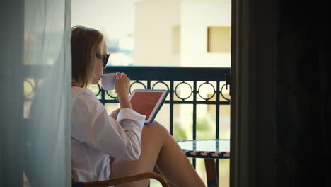 Young-woman-with-touchpad-on-hotel-balcony