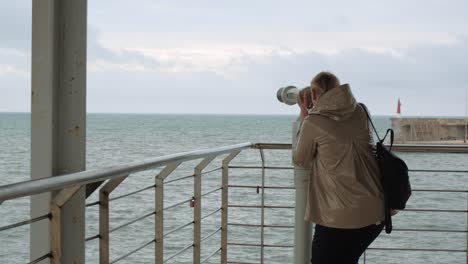 Woman-looking-at-sea-through-binoculars-at-view-point