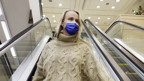 Woman-customer-in-mask-on-escalator-in-shopping-mall