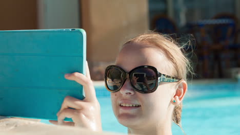 Young-woman-using-a-tablet-poolside