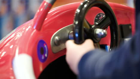 Child-turning-steering-wheel-of-a-toy-car