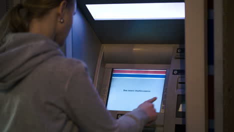 Woman-using-ATM-outdoor-in-the-evening