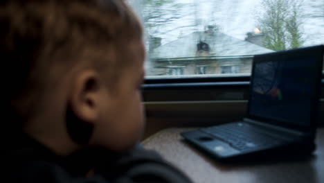 Boy-watching-movie-or-cartoon-on-laptop-in-the-train