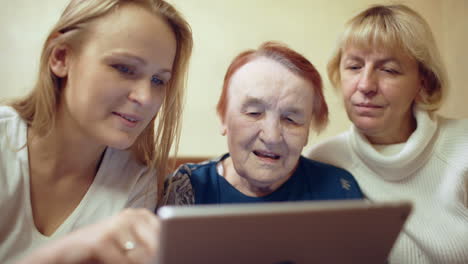 Woman-with-pad-showing-photos-or-video-to-her-mother-and-grandmother