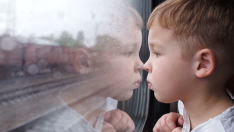 Curious-boy-looking-out-of-the-train-window-in-rainy-weather