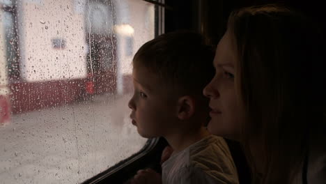 Mother-and-son-in-train-looking-out-the-window-on-a-rainy-day
