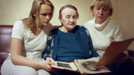 Daughter-mother-and-grandmother-looking-through-family-photos