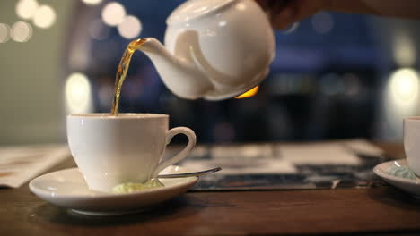 Pouring-black-hot-tea-into-the-cup