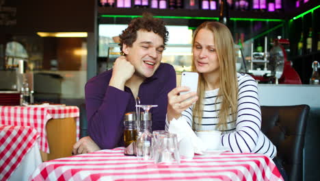 Young-couple-in-cafe-having-a-video-chat-on-smartphone