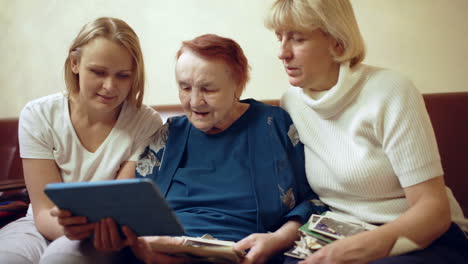 Family-of-three-women-looking-photos-on-touchpad