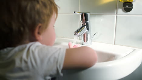 Boy-washing-hands-with-soft-soap-and-turning-off-water