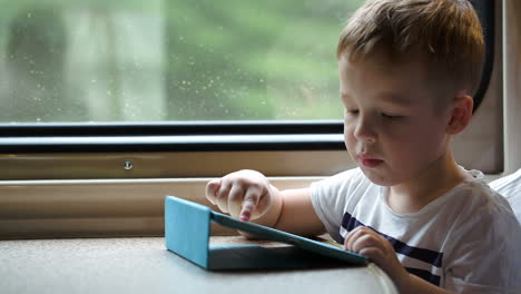 Boy-playing-on-pad-in-the-train-trying-to-win-without-mothers-help