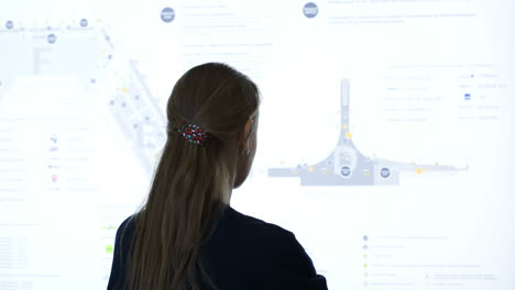 Woman-exploring-schematic-map-at-the-airport-or-trade-cemter