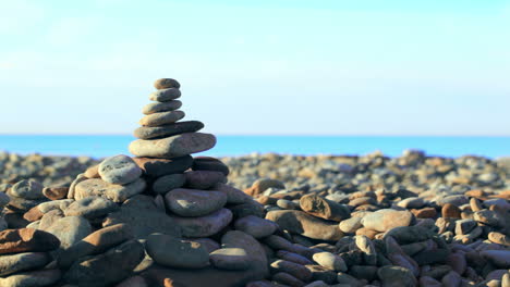 Hand-putting-last-stone-on-pyramid-at-the-seaside
