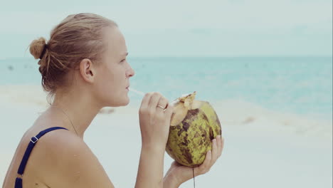 Woman-on-the-beach-drinking-from-coconut