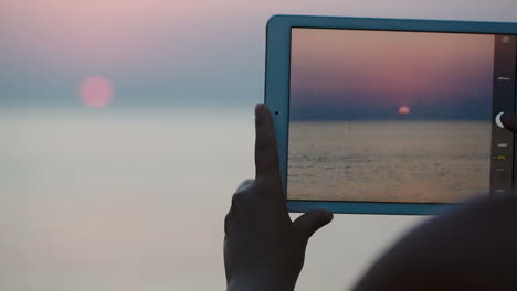 Taking-pictures-of-sunset-over-sea-with-touch-pad